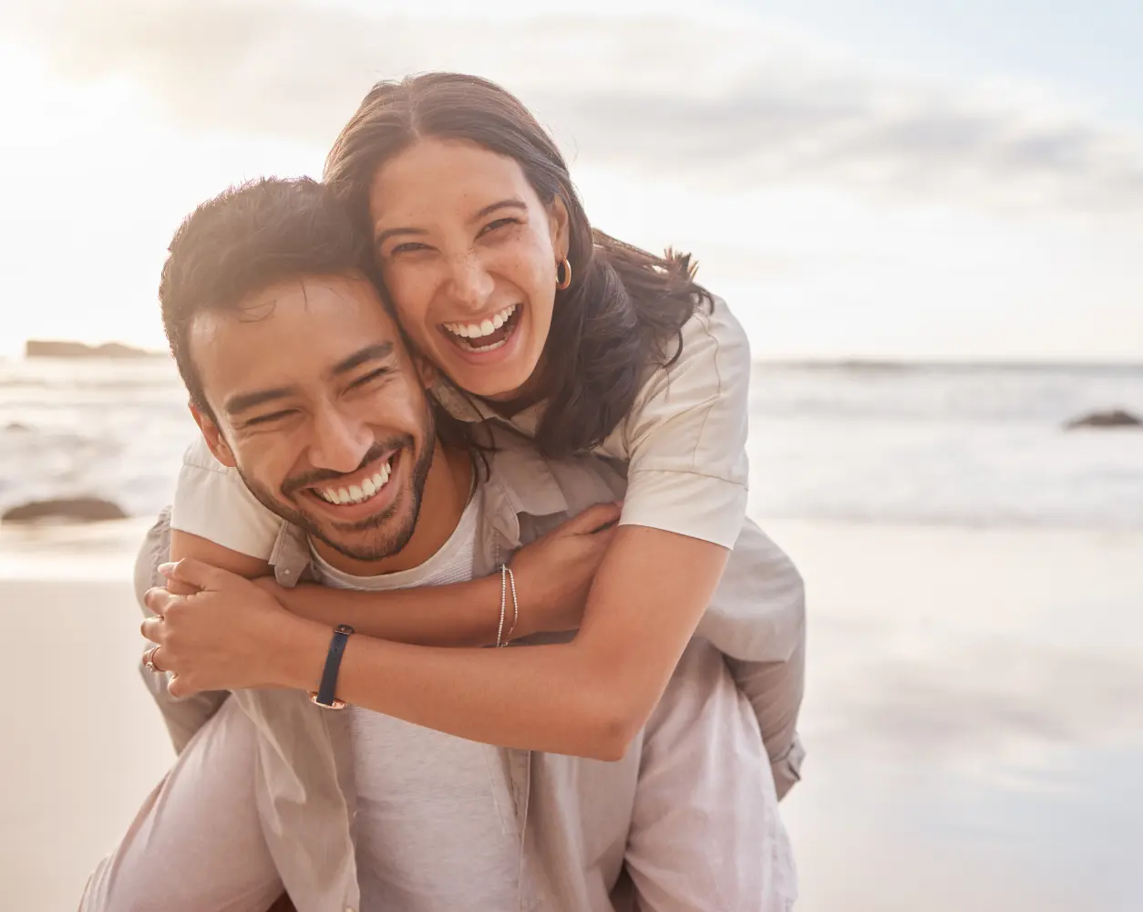 Smiling couple enjoying piggyback on beach.